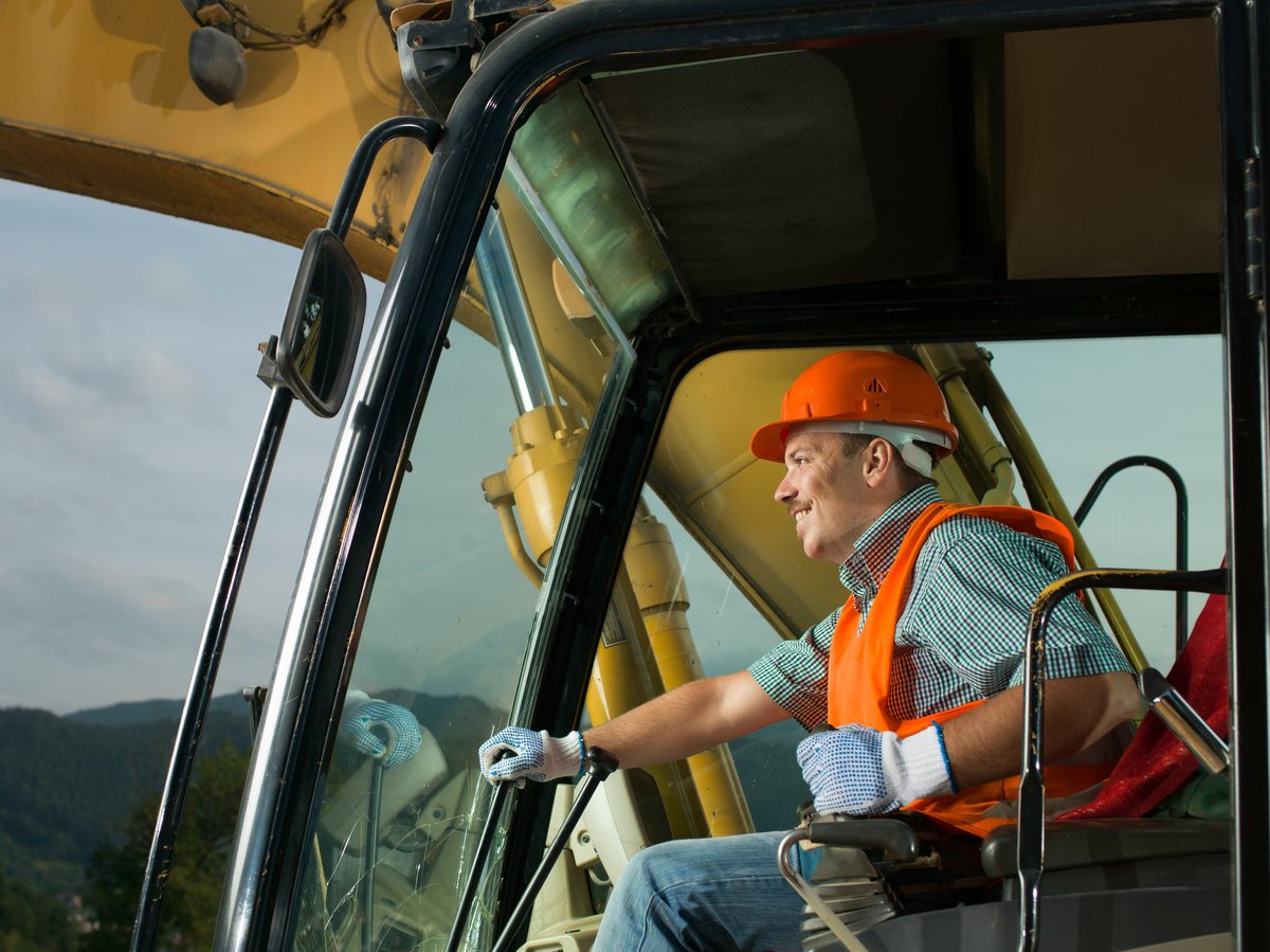 Male operator driving excavator on construction building site